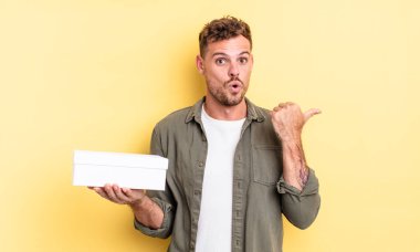 İnanamadığı için şaşırmış genç ve yakışıklı bir adam. beyaz kutu kavramı