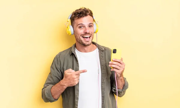 Jovem Homem Bonito Olhando Animado Surpreso Apontando Para Fones Ouvido — Fotografia de Stock