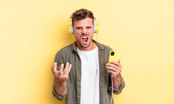 Mladý Pohledný Muž Vypadá Rozzlobený Otrávený Frustrovaný Sluchátka Smartphone Koncept — Stock fotografie