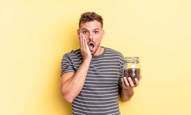 Genç yakışıklı adam şok olmuş ve korkmuş kahve çekirdekleri konsepti