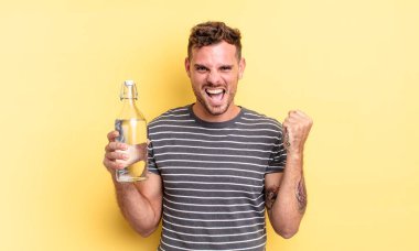 Genç yakışıklı adam şok olmuş hissediyor, gülüyor ve başarıyı kutluyor. su kavramı