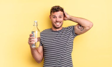 Genç ve yakışıklı bir adam stresli, endişeli ya da korkmuş hissediyor. Elleri başının üstünde. su kavramı