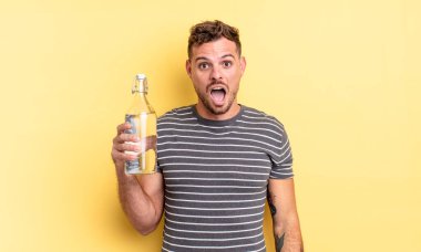 Genç ve yakışıklı bir adam çok şaşırmış ya da şaşkın görünüyor. su kavramı