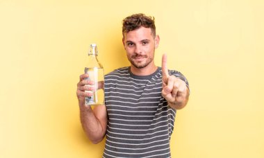 Genç yakışıklı adam gururla gülümsüyor ve kendinden emin bir numara oluyor. su kavramı