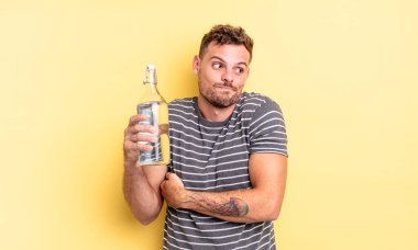 Genç yakışıklı adam omuz silkiyor, kafası karışık ve kararsız. su kavramı