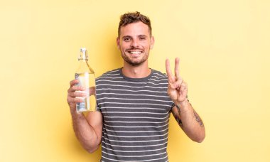 Genç yakışıklı adam gülümsüyor ve arkadaş canlısı görünüyor, iki numarayı gösteriyor. su kavramı