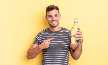 Genç yakışıklı adam neşeyle gülümsüyor, mutlu hissediyor ve bir tarafı işaret ediyor. su kavramı