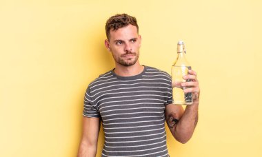 Genç ve yakışıklı bir adam üzgün, üzgün ya da kızgın hissediyor ve yan tarafa bakıyor. su kavramı