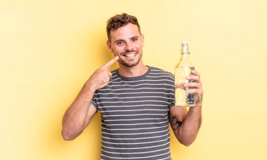 Genç ve yakışıklı bir adam kendi gülüşünü işaret ederek kendine güvenerek gülümsüyor. su kavramı