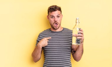 Şok olmuş ve ağzı açık, kendini işaret eden genç ve yakışıklı bir adam. su kavramı