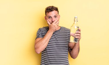 Genç ve yakışıklı bir adam elleri ile ağzını kapatıyor ve şok geçiriyor. su kavramı