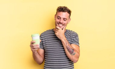 Genç ve yakışıklı bir adam mutlu ve kendinden emin bir ifadeyle gülümsüyor.