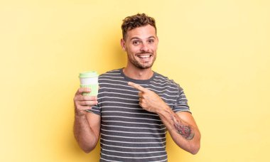 Genç yakışıklı adam heyecanlı ve şaşırmış görünüyor. Yan yemek konseptine işaret ediyor.