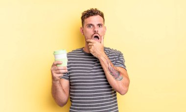 Ağzı ve gözleri açık, eli çenesinde genç ve yakışıklı bir adam.