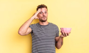 Genç yakışıklı adam mutlu görünüyor, şaşkın ve şaşırmış boş kase konsepti