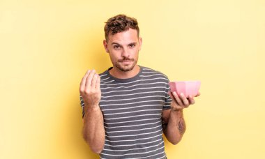 Genç yakışıklı adam kapiş ya da para hareketi yapıyor, sana boş kase konseptini ödemeni söylüyor.