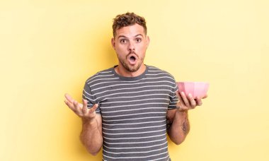 Genç yakışıklı adam şaşırdı, şaşırdı ve hayrete düştü. İnanılmaz boş kase konseptiyle.