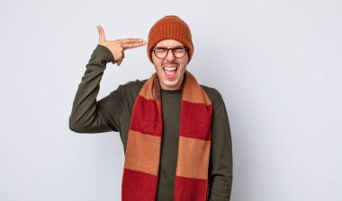 Genç yakışıklı adam mutsuz ve stresli görünüyor, intihar jesti silah işareti yapıyor. Kışlık kıyafet konsepti