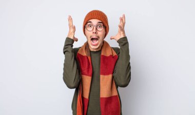 Genç yakışıklı adam ellerini havaya kaldırarak çığlık atıyor. Kışlık kıyafet konsepti