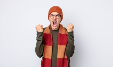 Genç yakışıklı adam sinirli bir ifadeyle agresif bir şekilde bağırıyor. Kışlık kıyafet konsepti