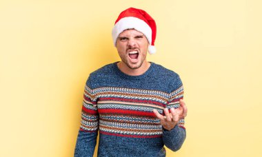 Genç ve yakışıklı bir adam sinirli, sinirli ve sinirli görünüyor. Noel konsepti