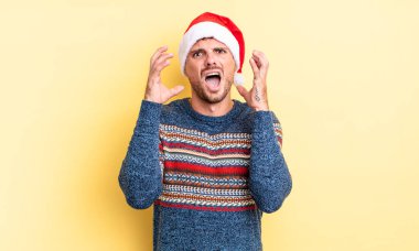 Genç yakışıklı adam ellerini havaya kaldırarak çığlık atıyor. Noel konsepti