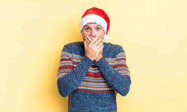 Genç ve yakışıklı bir adam elleri ile ağzını kapatıyor ve şok geçiriyor. Noel konsepti