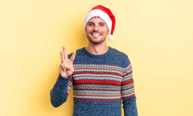 Genç yakışıklı adam gülümsüyor ve arkadaş canlısı görünüyor, üç numarayı gösteriyor. Noel konsepti