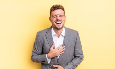 Genç yakışıklı bir adam komik bir şakaya yüksek sesle gülüyor. iş kavramı