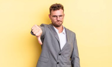 Genç ve yakışıklı bir adam kendini kötü hissediyor, baş parmağını kaldırıyor. iş kavramı