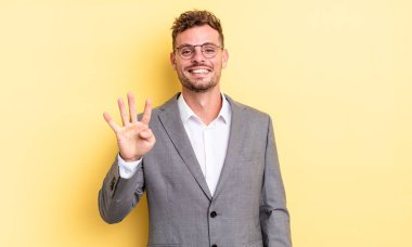 young handsome man smiling and looking friendly, showing number four. business concept