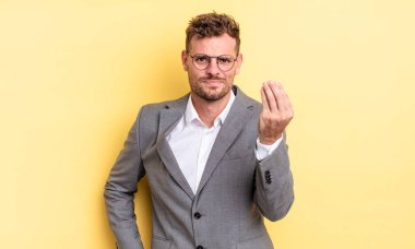 young handsome man making capice or money gesture, telling you to pay. business concept