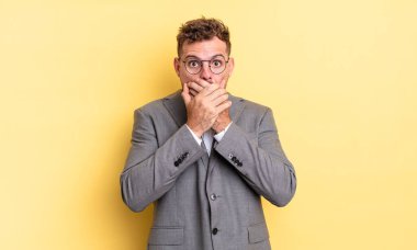 Genç ve yakışıklı bir adam elleri ile ağzını kapatıyor ve şok geçiriyor. iş kavramı
