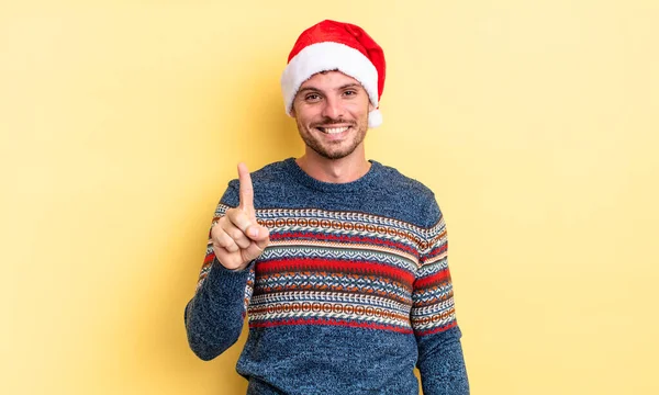 若いハンサムな男は笑顔で友好的に見えます1番を示しています クリスマスのコンセプト — ストック写真