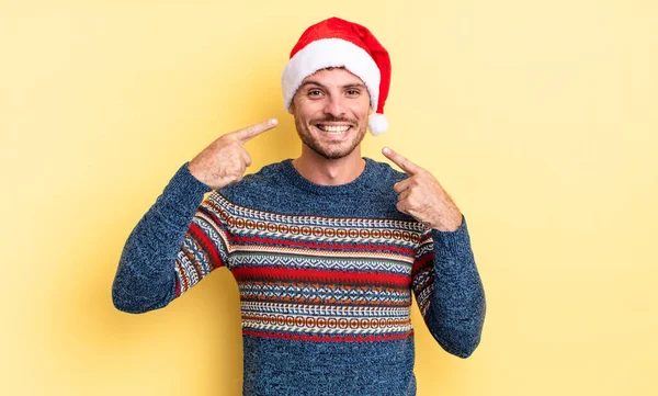 若いハンサムな男は自信を持って笑顔を指す クリスマスのコンセプト — ストック写真