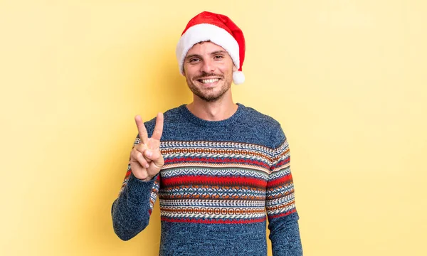 若いハンサムな男は笑顔で友好的に見える2番目を示しています クリスマスのコンセプト — ストック写真