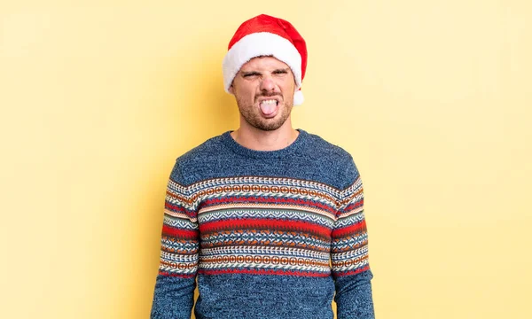 若いハンサムな男はうんざりしていらいらして舌を出す クリスマスのコンセプト — ストック写真