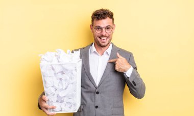 Genç yakışıklı adam mutlu hissediyor ve heyecanlı bir kağıt topuyla kendini işaret ediyor. Çöp konsepti.