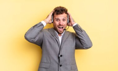 Genç ve yakışıklı bir adam stresli, endişeli ya da korkmuş hissediyor. Elleri başının üstünde. Tele-pazarlamacı ortak.