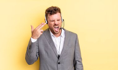 Genç yakışıklı adam mutsuz ve stresli görünüyor, intihar jesti silah işareti yapıyor. Tele-pazarlamacı ortak.