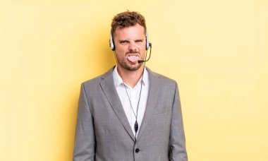 Genç ve yakışıklı bir adam tiksinmiş ve sinirlenmiş hissediyor ve dilini dışarı çıkarıyor. Tele-pazarlamacı ortak.