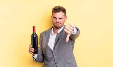 Genç ve yakışıklı bir adam kendini kötü hissediyor, baş parmağını kaldırıyor. Şarap şişesi konsepti