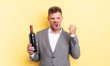 Genç yakışıklı adam sinirli bir ifadeyle agresif bir şekilde bağırıyor. Şarap şişesi konsepti