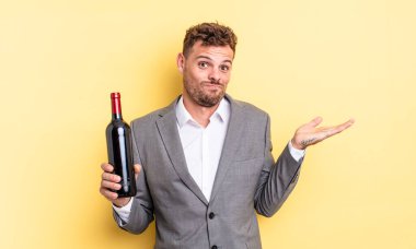 Genç yakışıklı adam şaşkın, şaşkın ve şüpheci hissediyor. Şarap şişesi konsepti