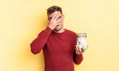 Genç, yakışıklı adam şok olmuş, korkmuş ya da korkmuş görünüyor. jöle şekeri konsepti