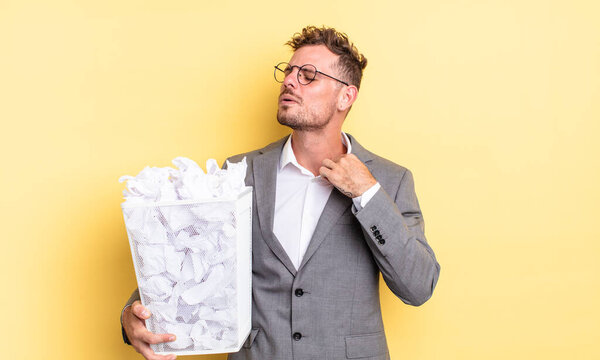 young handsome man feeling stressed, anxious, tired and frustrated paper balls trash concept
