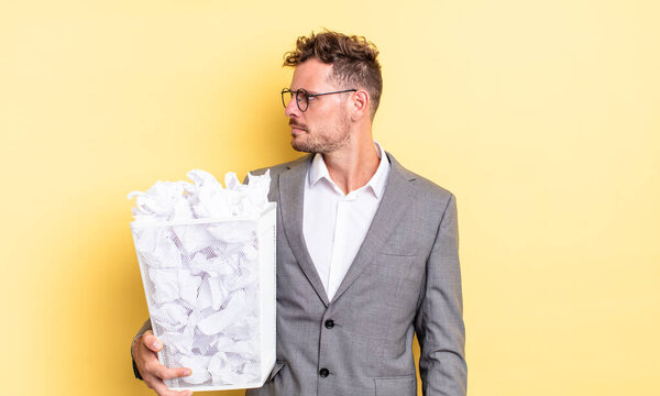 young handsome man on profile view thinking, imagining or daydreaming paper balls trash concept