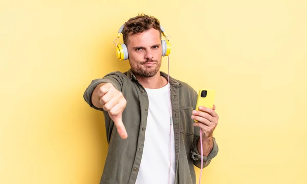 Mladý Pohledný Muž Pocit Kříže Ukazující Palce Dolů Sluchátka Smartphone — Stock fotografie