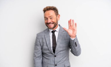 Orta yaşlı yakışıklı adam mutlu bir şekilde gülümsüyor, el sallıyor, seni selamlıyor ve selamlıyor. İş adamı konsepti