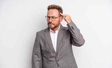 Orta yaşlı yakışıklı bir adam kafası karışık ve şaşkın hissediyor, deli olduğunu gösteriyor. İş adamı konsepti